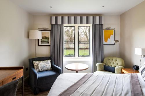 a hotel room with a bed and a chair and a window at voco Oxford Thames by IHG in Oxford