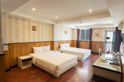 a hotel room with two beds and a desk at Golden Rain 2 Hotel in Nha Trang