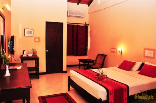 ダンブッラにあるGimanhala Hotelのベッドとデスクが備わるホテルルームです。