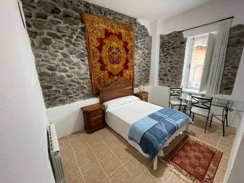 1 dormitorio con cama y pared de piedra en Hotel El Nuevo Semellon 