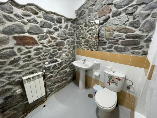 a stone bathroom with a toilet and a sink at Hotel El Nuevo Semellon 