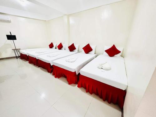 eine Reihe von Betten in einem Zimmer mit roten Kissen in der Unterkunft Red Palm Inn studio room with Netflix in Baybay