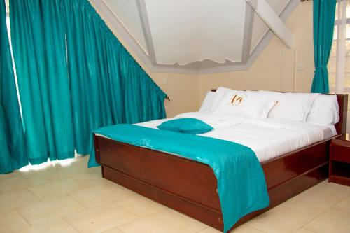 a bedroom with a large bed with blue curtains at Mojoh Inn Hotel in Ambira