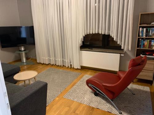 uma sala de estar com uma cadeira vermelha e uma televisão em Haus Nummer Vier em Neunkirchen