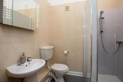 La salle de bains est pourvue de toilettes, d'un lavabo et d'une douche. dans l'établissement Stables Cottage, à Selby