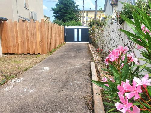une allée en face d'une clôture avec des fleurs roses dans l'établissement Sweety house, à Brive-la-Gaillarde