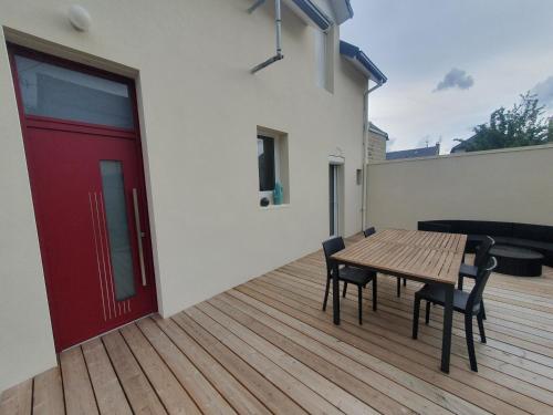 Sweety house في بريف لا غايلارد: طاولة وكراسي خشبية على سطح مع باب احمر