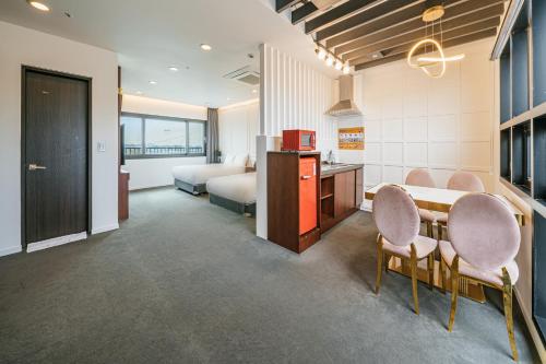 een kamer met een tafel en stoelen en een slaapkamer bij Drama 2015 in Jeju-stad
