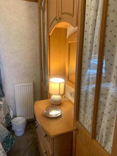 a bedroom with a dresser with a lamp on it at Farm stay caravan on working farm in Dacre