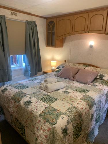 a bedroom with a bed with a quilt on it at Farm stay caravan on working farm in Dacre
