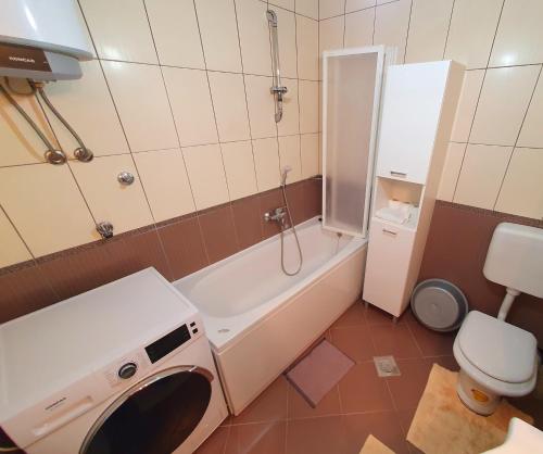 a bathroom with a tub and a toilet and a washing machine at Luxury Penthouse in Široki Brijeg