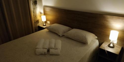 a bed with two white pillows and two lights on it at Apartamento Confortável em Capão in Capão da Canoa