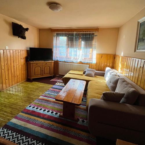 ein Wohnzimmer mit einem Sofa und einem Tisch in der Unterkunft Casuta noastra din Predeal in Predeal