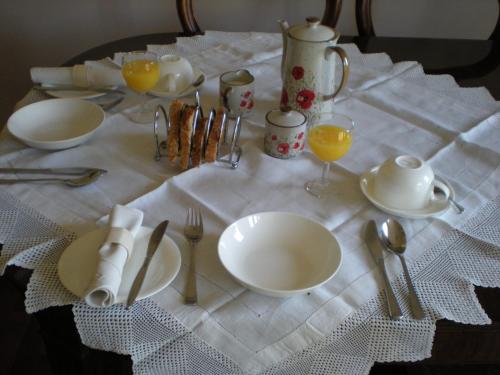 einen Tisch mit Tellern und Küchenutensilien auf einem weißen Tischtuch in der Unterkunft Hillside Cottage in Ledbury