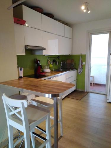 une cuisine avec une table en bois et des armoires blanches dans l'établissement Appartement confortable centre ville, à LʼIsle-sur-la-Sorgue