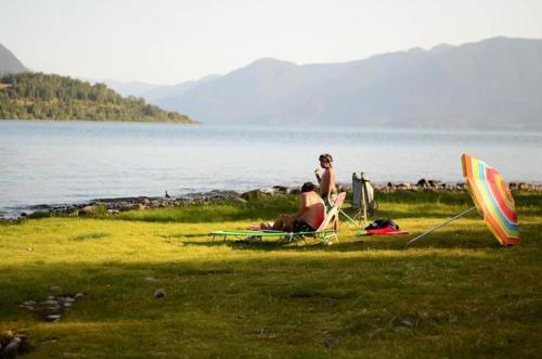 two people sitting in a field near the water with a kite at Tiny House & Loft House in Panguipulli