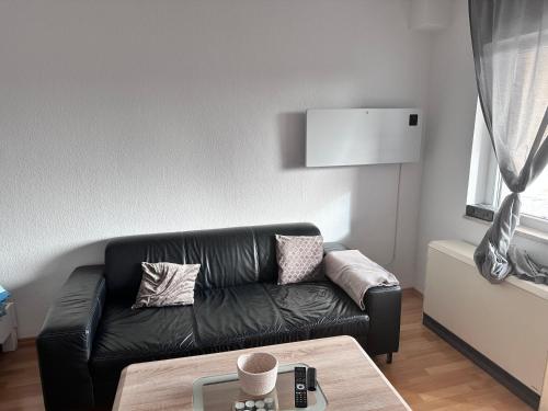 a living room with a black leather couch and a table at M&L Wohnen 2 in Essen