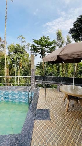 a table and an umbrella next to a swimming pool at Sana Riverside in Madikeri