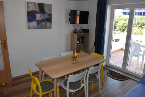 a dining room with a wooden table and yellow chairs at Apartment Vitezic in Punat