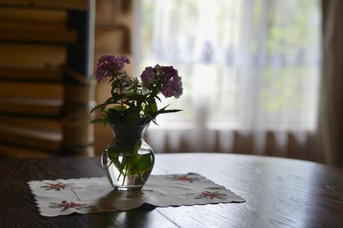 a vase with purple flowers sitting on a table at Садиба BETWEEN MOUNTAINS in Mizhhirʼʼya