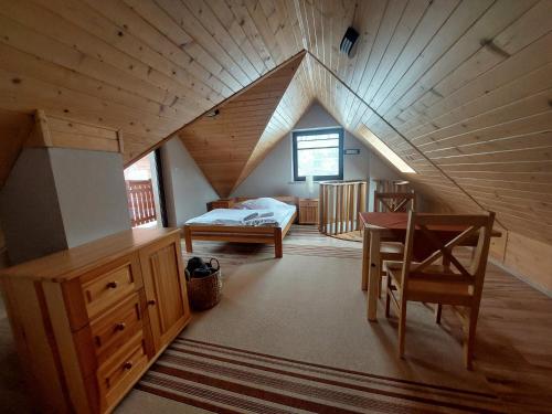 スロモフツェ・ビジネにあるWilla Przekop - apartamentyのベッド、デスク、テーブルが備わる屋根裏部屋です。