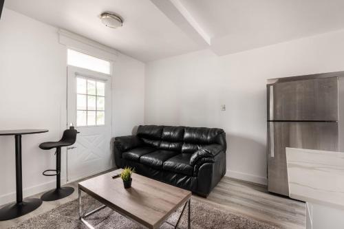 - un canapé en cuir noir dans un salon avec une table dans l'établissement 2 bedroom apartment - 1005, à Montréal