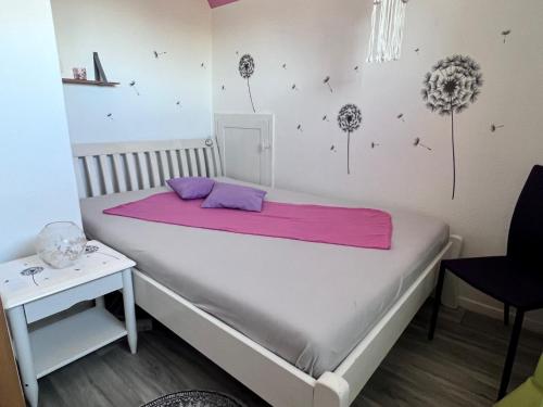 Ferienhaus am Mühlgraben في ثال: غرفة نوم مع سرير مع بطانية وردية عليه