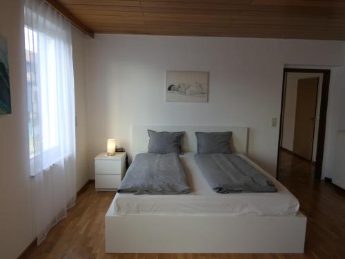 a white bedroom with a bed and a window at Historische Villa im Herzen Rankweils in Rankweil