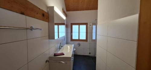 baño blanco con lavabo y ventana en Schönste Ferienwohnung mit Panoramablick in Ftan im Unterengadin en Ftan