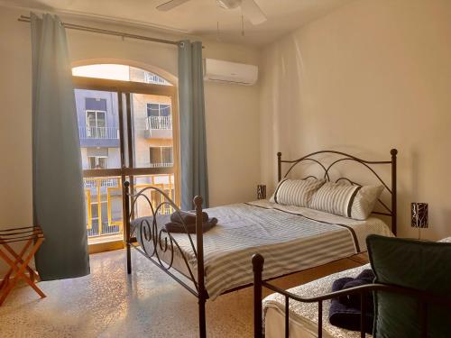 um quarto com uma cama e uma grande janela em Seaside Urban Edge Suites- w/3BR em St. Paul's Bay