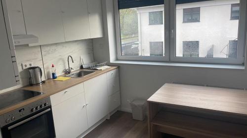 eine Küche mit weißen Schränken, einem Waschbecken und einem Fenster in der Unterkunft Wohnung Thea in Hannover