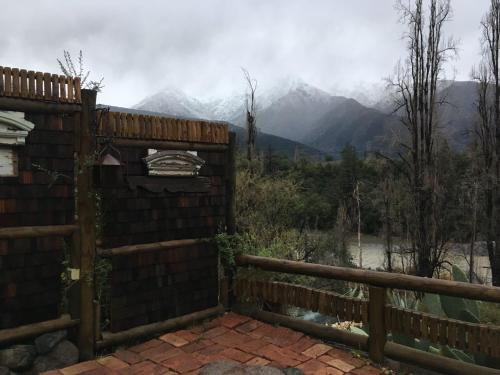 a house with a fence and mountains in the background at Loft del Rio in Cajon del Maipo