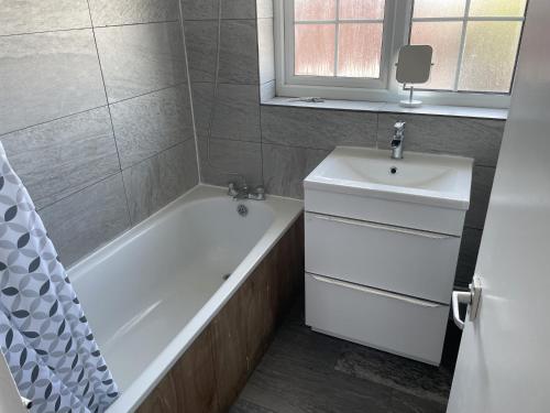 a bathroom with a white tub and a sink at A nice double bedroom in Mottingham in Eltham