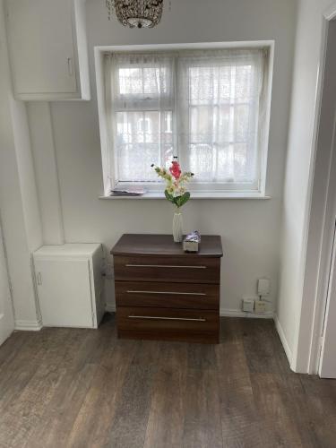 a vase of flowers on a dresser in a room at A nice double bedroom in Mottingham in Eltham