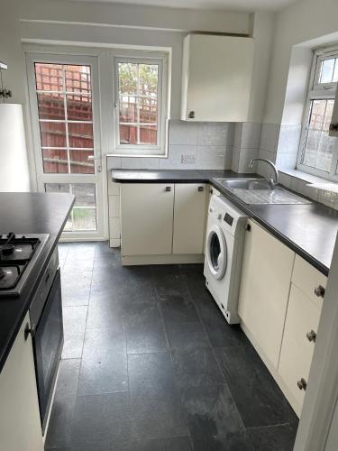 a kitchen with a sink and a washing machine at A nice double bedroom in Mottingham in Eltham
