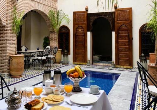 un tavolo con cibo e frutta accanto a una piscina di Riad Touhfa Kasbah Marrakech a Marrakech