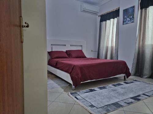 a bedroom with a bed with a red comforter at Siar Apartment in Tirana