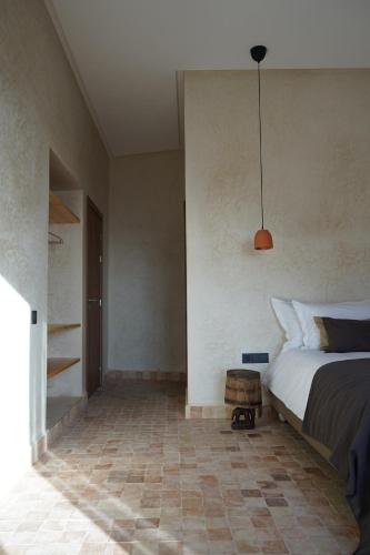 L'Oued the lodge في إمسوان: غرفة نوم بها سرير و قلادة خفيفة