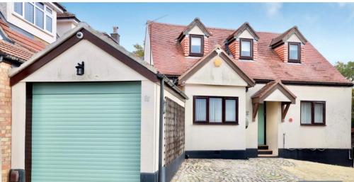 una casa con una puerta de garaje delante de ella en 81 Theydon park road, en Theydon Bois