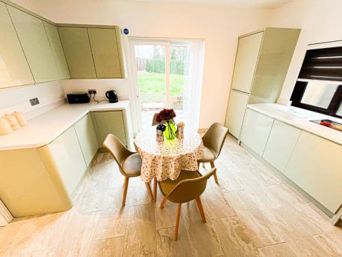 una pequeña cocina con mesa, sillas y ventana en 81 Theydon park road, en Theydon Bois