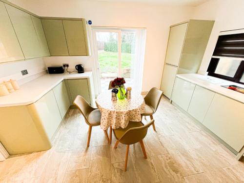 a small kitchen with a table and chairs and a window at 81 Theydon park road in Theydon Bois