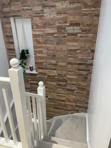 a faux brick accent wall in a stairwell with a white stair railing at 81 Theydon park road in Theydon Bois