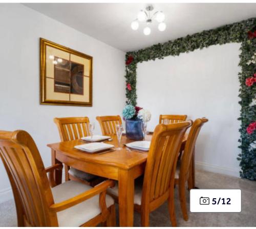 a dining room with a wooden table and chairs at 81 Theydon park road in Theydon Bois