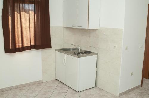 a small kitchen with a sink and white cabinets at Apartments Jadrijević Brne in Primošten
