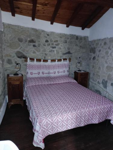 a bedroom with a pink bed in a stone wall at Casa museo "Sa domu de ziu Antoneddu" in Tuili