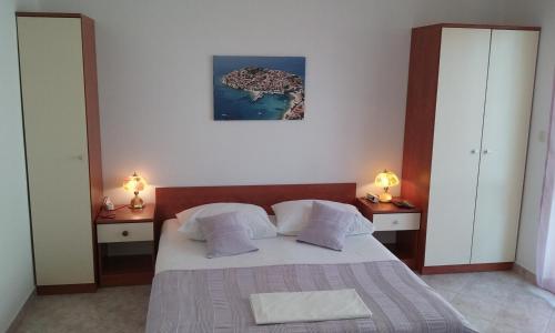 a bedroom with a bed with two night stands and two lamps at Apartments Jadrijević Brne in Primošten