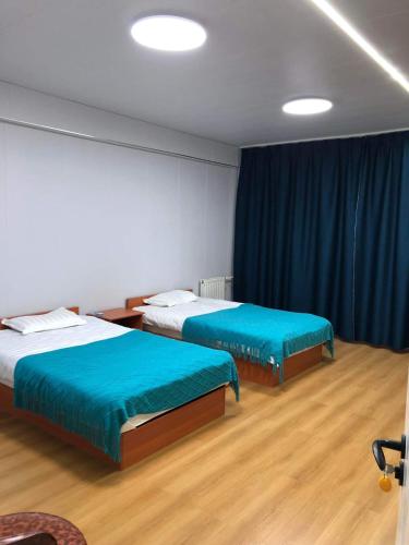 two beds in a room with blue sheets and wood floors at Etuga Guesthouse, Close to Sukhbaatar Square in Ulaanbaatar