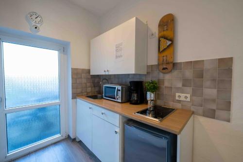 eine kleine Küche mit einer Spüle und einer Mikrowelle in der Unterkunft Messe Apartment Neuss Düsseldorf in Neuss