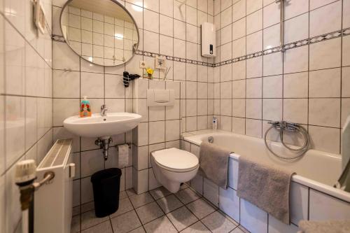 a white bathroom with a sink and a toilet and a tub at Messe Apartment Neuss Düsseldorf in Neuss