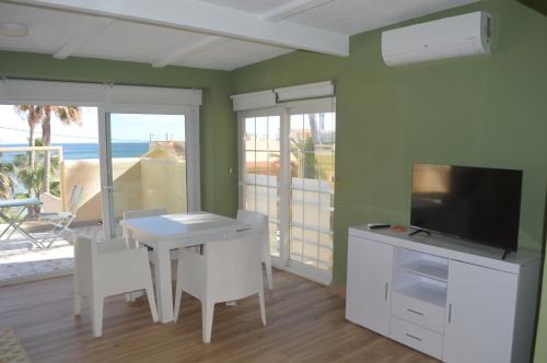 uma sala de jantar com uma mesa, uma televisão e uma varanda em Extraordinario apartamento a pie de playa en Chalet Roquetes em Alicante